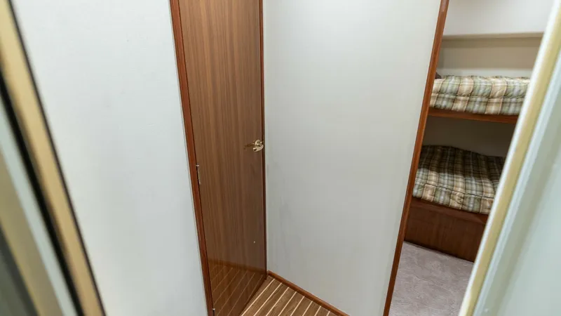 Slide: The Image of Guest Cabin Entrance and Berths This image showcases the entrance to the guest cabin featuring twin berths with plaid bedding. The wooden flooring and door add a touch of elegance, enhancing the cozy yet functional space. Ideal for accommodating guests, this cabin offers comfort and pri - 6394746