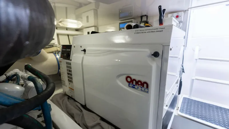 Slide: The Image of Engine Room with Onan Generator This image showcases the well-maintained engine room of the 2007 Viking 45 Convertible, featuring a robust Onan generator. The space is organized with neatly arranged components and accessible panels for easy maintenance. Bright lighting and clean surface - 6394747