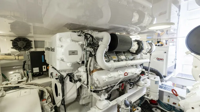Slide: The Image of Engine Room with Main Engine This image showcases the pristine engine room of the 2007 Viking 45 Convertible, featuring a robust marine diesel engine. The space is well-organized, with clean, white finishes and accessible maintenance areas, emphasizing the vessel's commitment to perf - 6394751