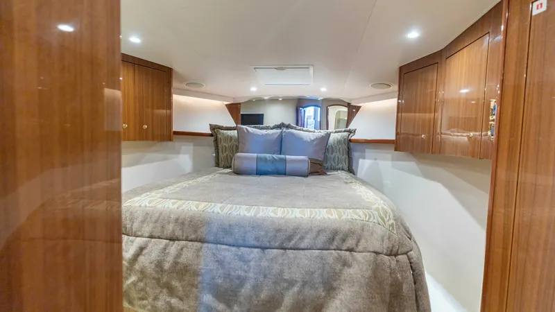 Slide: The Image of Luxurious Forward Stateroom The forward stateroom of the 2007 Viking 45 Convertible 'Desperado' offers a plush queen-sized berth surrounded by high-gloss wood cabinetry. Elegant lighting complements the warm wood finishes, creating a cozy yet sophisticated ambiance. Ample storage an - 6394720