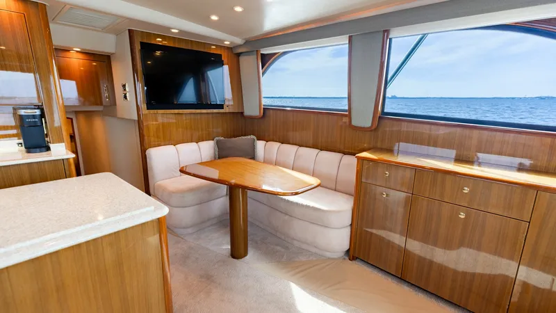 Slide: The Image of Salon with Dinette and Ocean Views This inviting salon on the 2007 Viking 45 Convertible features a plush, curved dinette set against expansive ocean-view windows. The warm wood cabinetry and contemporary finishes create a cozy yet elegant atmosphere. Natural light enhances the open layout - 6394725
