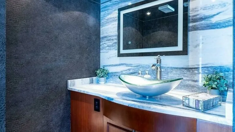 Slide: The Image of Elegant Yacht Bathroom Vanity This luxurious bathroom on the Magnum Ride features a stunning glass vessel sink atop a sleek marble countertop. The polished wood cabinetry adds warmth, while the marble backsplash provides an elegant touch. Subtle lighting and modern fixtures complete t - 6388385