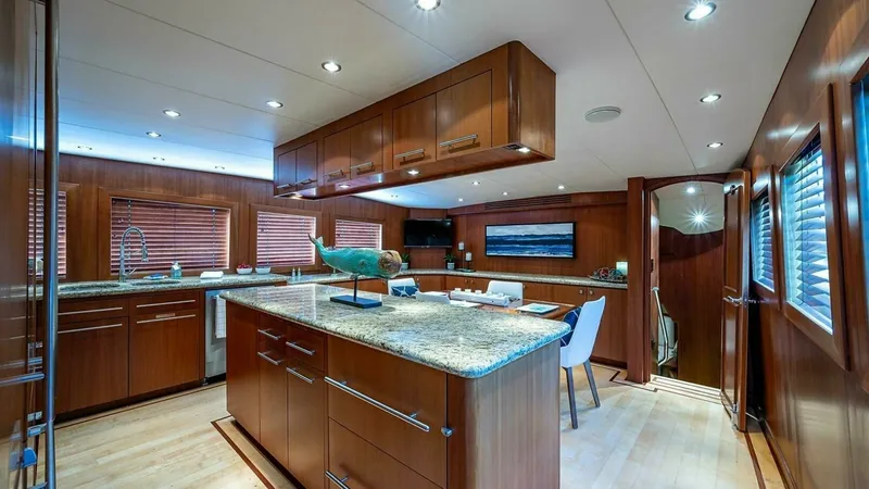 Slide: The Image of Spacious Galley with Island This well-appointed galley features a central island with granite countertops, offering ample space for meal preparation and casual dining. The warm wooden cabinetry provides abundant storage, complemented by modern stainless steel appliances. Recessed li - 6388387