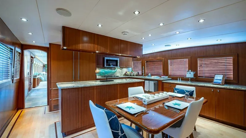 Slide: The Image of Elegant Galley and Dining Area This spacious galley aboard the 2003 Hatteras Raised Pilothouse features exquisite wood cabinetry and modern appliances, creating a luxurious and functional space for dining and entertaining. The elegant dining table is set with nautical-themed decor, com - 6388388