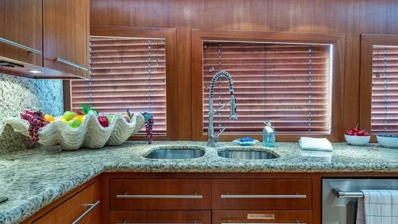 Slide: The Image of Galley with Granite Countertops The galley of the 2003 Hatteras Raised Pilothouse features elegant granite countertops and rich wooden cabinetry. Twin stainless steel sinks are complemented by a modern high-arch faucet, providing both functionality and style. Large windows with wooden b - 6388390