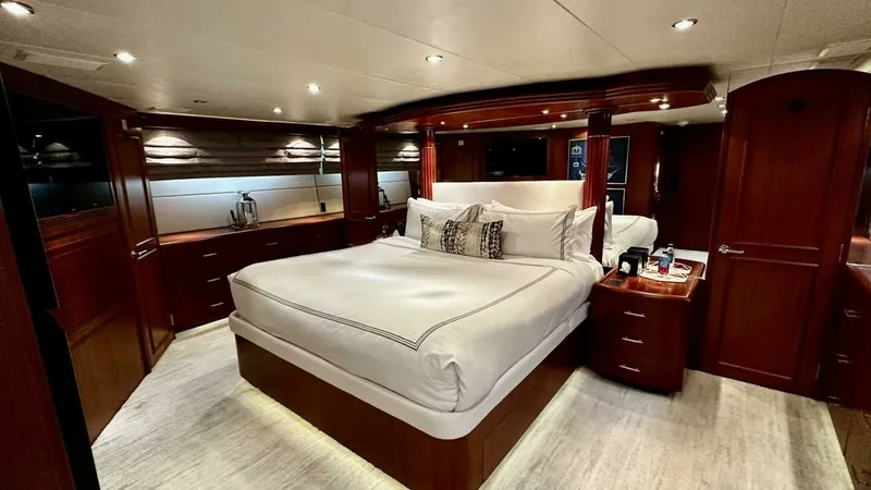 Slide: The Image of Luxurious Master Stateroom This elegant master stateroom features a spacious layout with a plush, centrally positioned bed surrounded by rich wood cabinetry. Ambient recessed lighting and large windows create a warm, inviting atmosphere, while ample storage and fine finishes enhanc - 6388377