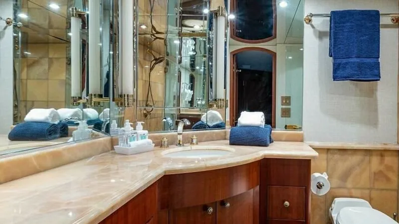 Slide: The Image of Luxurious Ensuite Bathroom This elegant ensuite bathroom on the Magnum Ride features a beautifully crafted marble countertop and rich wooden cabinetry. The mirrored walls enhance the spacious feel, while the ambient lighting provides a warm and inviting atmosphere. Modern fixtures - 6388397