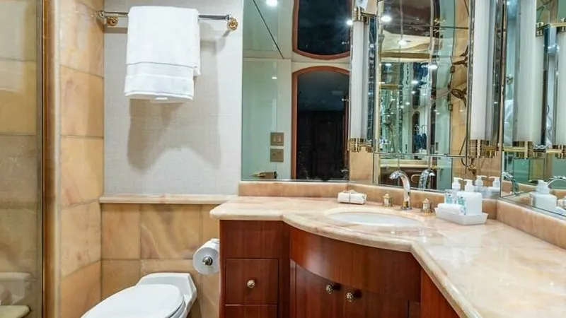 Slide: The Image of Luxurious Yacht Bathroom This elegant yacht bathroom features rich wood cabinetry and a polished marble countertop, exemplifying luxury and sophistication. The mirrored wall enhances the sense of space and light, while the high-quality fixtures and ample storage add practicality. - 6388399