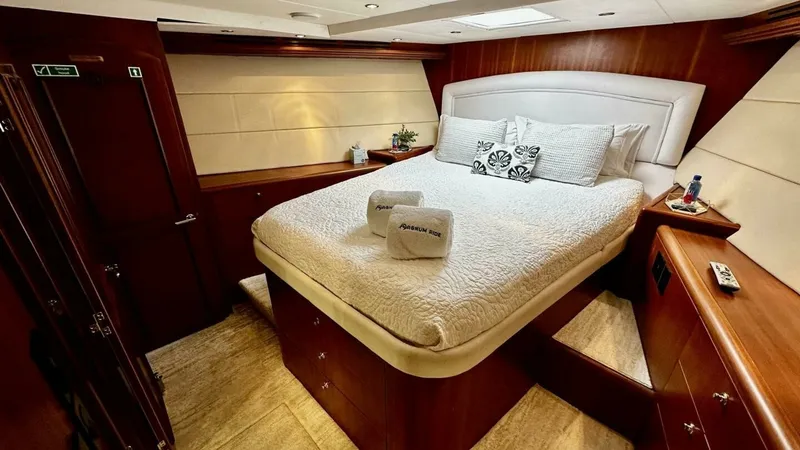 Slide: The Image of Master Stateroom with Queen Bed The master stateroom offers a cozy and inviting atmosphere, featuring a plush queen-sized bed adorned with elegant linens. Rich wood cabinetry and paneling provide ample storage and enhance the luxurious feel of the space. Soft, ambient lighting complemen - 6388400