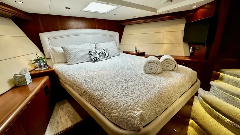 Slide: The Image of Luxurious Master Stateroom The master stateroom offers a spacious and inviting retreat, featuring a plush queen-sized bed with elegant bedding. Rich wood paneling and ambient lighting create a warm and sophisticated atmosphere, while the built-in flat-screen TV adds modern convenie - 6388401