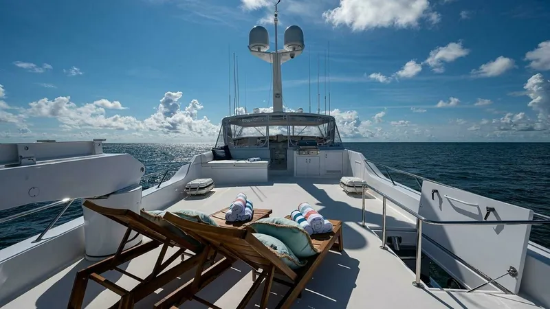 Slide: The Image of Spacious Sun Deck with Loungers This expansive sun deck on the 2003 Hatteras Magnum Ride features comfortable wooden loungers, perfect for relaxing under the open sky. The area is complemented by plush cushions and rolled towels, inviting guests to unwind while enjoying panoramic ocean - 6388378