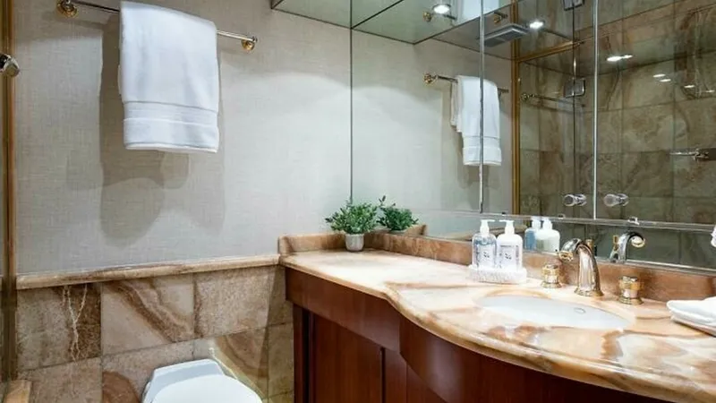 Slide: The Image of Elegant Yacht Bathroom Interior This luxurious yacht bathroom features a beautifully crafted marble countertop and a stylish wooden vanity. The space is elegantly appointed with a large mirror and soft, ambient lighting, enhancing the sense of openness. High-end fixtures and a glass-enc - 6388408