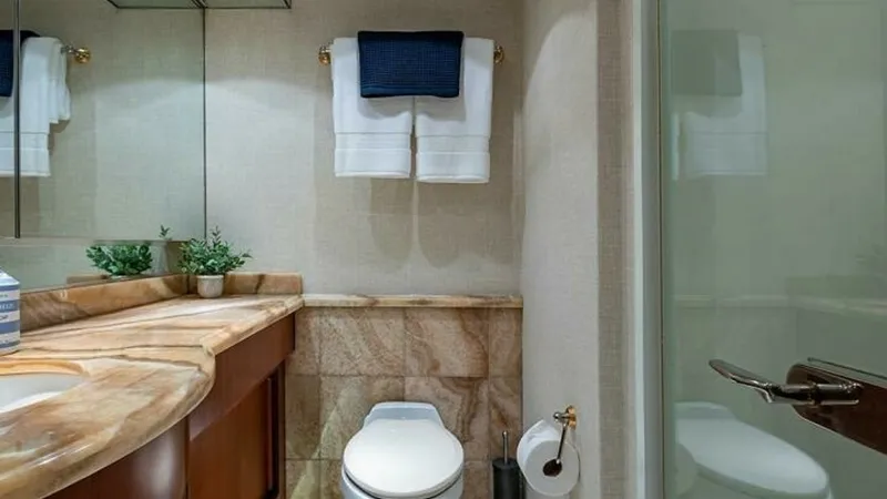 Slide: The Image of Elegant Guest Bathroom This guest bathroom on the 2003 Hatteras Raised Pilothouse features a sophisticated design with a marble countertop and polished wood cabinetry. The space is well-lit and includes a glass-enclosed shower, adding a touch of luxury to the vessel. Thoughtful - 6388410