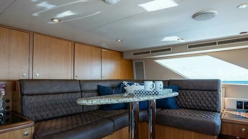 Slide: The Image of Salon Seating Area with Table The salon of the 2003 Hatteras Raised Pilothouse features a cozy seating area with plush, quilted upholstery, perfect for relaxation. A stylish granite-topped table provides an ideal spot for casual dining or enjoying a coffee. The space is enhanced by na - 6388415