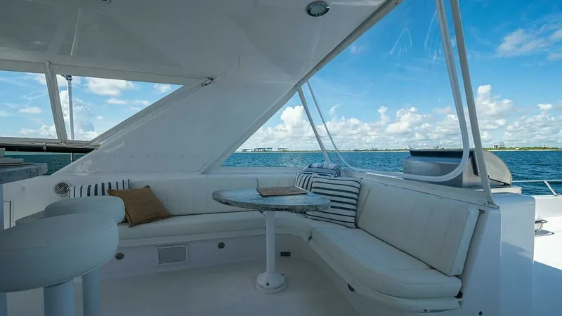 Slide: The Image of Flybridge Seating Area with Ocean Views This inviting flybridge on the 2003 Hatteras Raised Pilothouse features a comfortable L-shaped seating arrangement, perfect for relaxing and enjoying the ocean views. The area is elegantly designed with crisp white upholstery and complemented by a sleek w - 6388423