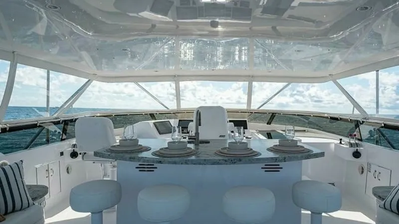 Slide: The Image of Flybridge with Bar and Seating This inviting flybridge on the 2003 Hatteras Magnum Ride features a sleek bar area with elegant granite countertops and comfortable barstools. The area is designed for both relaxation and entertainment, offering panoramic ocean views through expansive win - 6388424