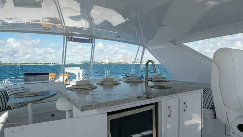 Slide: The Image of Flybridge Wet Bar and Seating Area This inviting flybridge features a sleek wet bar with a granite countertop and built-in sink, perfect for entertaining. The setup includes comfortable seating with striped cushions, offering a relaxed atmosphere for enjoying panoramic ocean views. The are - 6388426