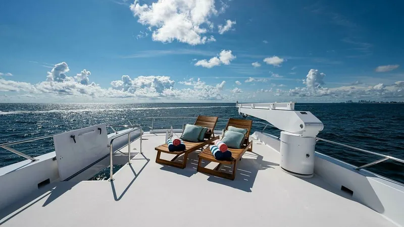 Slide: The Image of Spacious Sun Deck with Loungers Experience luxury and relaxation on the expansive sun deck of the 2003 Hatteras Raised Pilothouse. This area features stylish wooden loungers, perfect for sunbathing while enjoying panoramic ocean views. The clean, open layout enhances the serene atmosphe - 6388432