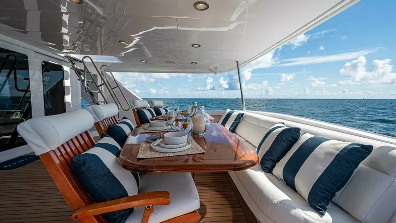 Slide: The Image of Spacious Aft Deck Dining Area This inviting aft deck features a beautifully set dining table surrounded by plush seating, perfect for enjoying meals with a panoramic ocean view. The area is elegantly designed with a combination of cushioned benches and wooden chairs, complemented by n - 6388434