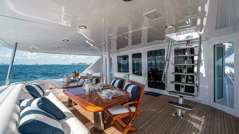 Slide: The Image of Spacious Aft Deck with Dining Area The aft deck of the 2003 Hatteras Raised Pilothouse, Magnum Ride, features a luxurious outdoor dining area. It is equipped with a beautifully crafted wooden table surrounded by plush seating, perfect for alfresco dining while enjoying ocean views. The tea - 6388437