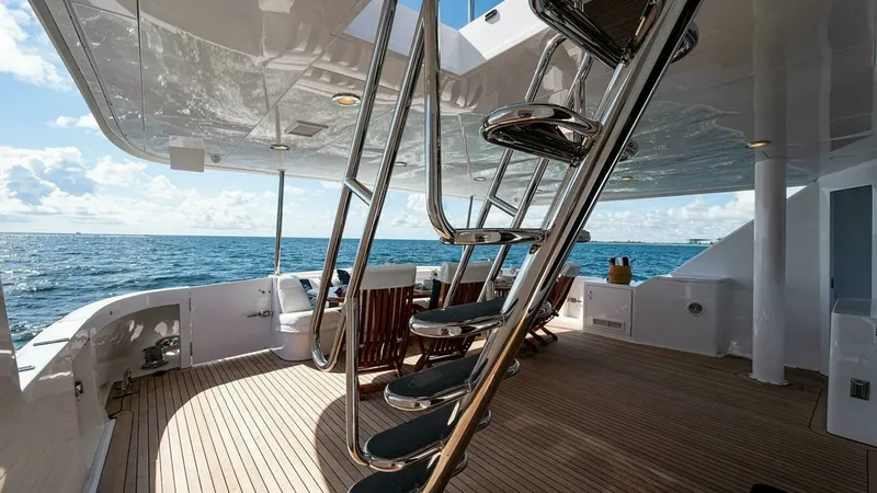 Slide: The Image of Aft Deck with Ladder Access This spacious aft deck features elegant teak flooring and a sleek, polished ladder leading to the upper levels. The area is designed for relaxation and entertainment, offering stunning ocean views and comfortable seating options. The overhead canopy provi - 6388439