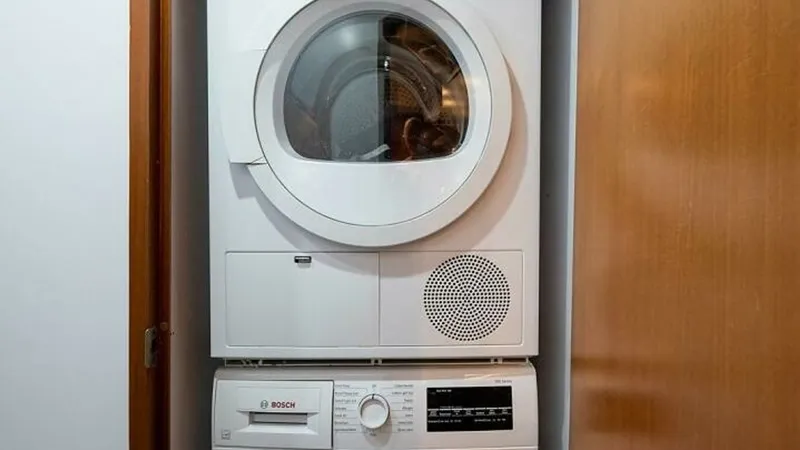 Slide: The Image of Compact Laundry Area with Bosch Appliances The image showcases a neatly designed laundry area on the Magnum Ride, featuring a stacked Bosch washer and dryer. Tucked away behind sleek wooden cabinetry, the appliances offer efficiency and modern convenience aboard the 2003 Hatteras Raised Pilothouse - 6388442