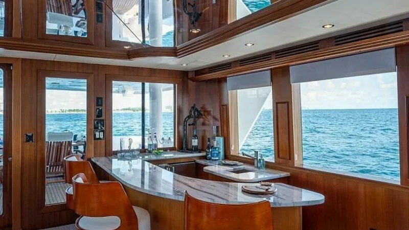 Slide: The Image of Galley with Ocean View This elegant galley on the 2003 Hatteras Magnum Ride features a sleek, curved countertop with integrated sink and modern appliances. The warm wooden cabinetry complements the plush seating, offering a cozy yet luxurious atmosphere. Expansive windows provi - 6388382