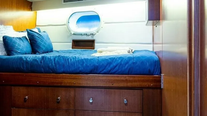 Slide: The Image of Cozy Guest Stateroom This inviting guest stateroom features a comfortable berth with plush bedding, complemented by rich wooden cabinetry offering ample storage space. A round porthole allows natural light to fill the room, enhancing the warm ambiance. The elegant design and - 6388445