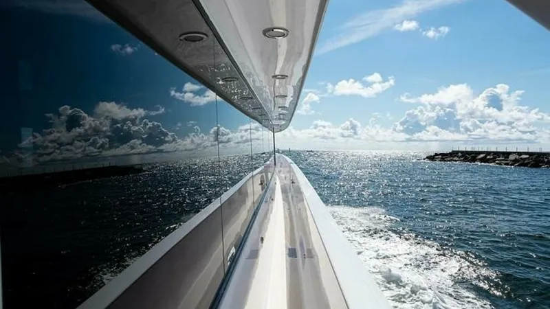 Slide: The Image of Reflective Side Deck View This image captures the sleek side deck of the Magnum Ride, showcasing the stunning reflective glass that mirrors the ocean and sky. The polished rails and streamlined design emphasize the vessel's elegance, while the expansive water views highlight its n - 6388446