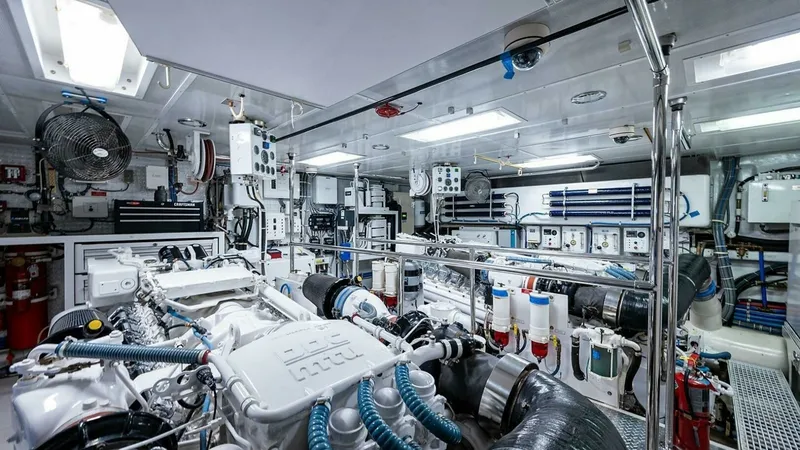Slide: The Image of Engine Room with Twin Engines The engine room of the 2003 Hatteras Magnum Ride features twin engines, showcasing a meticulously organized space with high-quality engineering. Bright overhead lighting highlights the clean, efficient layout, complete with essential equipment and advance - 6388458