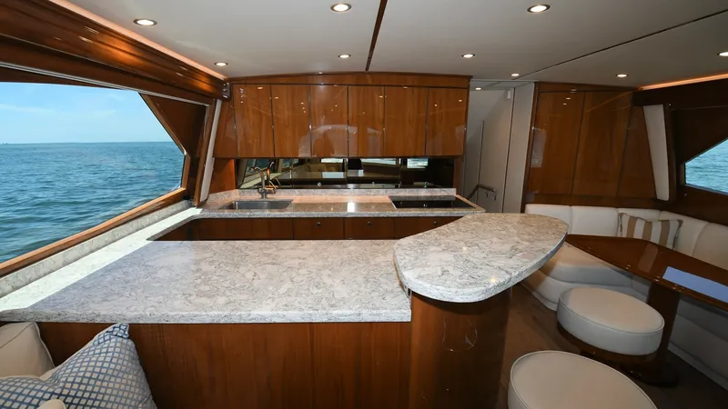 Slide: The Image of Galley and Dinette with Ocean View The 2020 Viking 58 Convertible features a sophisticated galley with elegant marble countertops and rich wood cabinetry, offering ample storage and workspace. Adjacent to the galley, the cozy dinette provides a comfortable seating area for dining or relaxa - 6388295