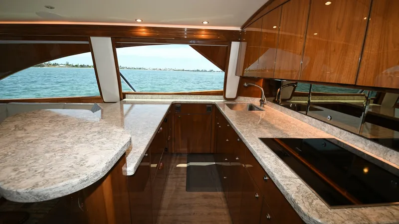 Slide: The Image of Galley with Ocean View The galley of the 2020 Viking 58 Convertible showcases elegant wood cabinetry and sleek countertops, providing a luxurious cooking space. Large windows offer breathtaking ocean views, enhancing the open and airy atmosphere. Modern appliances and ample sto - 6388297