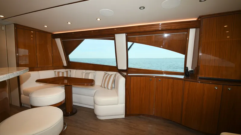 Slide: The Image of Spacious Salon with Ocean View This inviting salon on the 2020 Viking 58 Convertible features plush seating and a sleek wooden table, perfect for relaxation or entertaining guests. Large windows offer sweeping ocean views, enhancing the luxurious and airy atmosphere. The high-quality w - 6388298