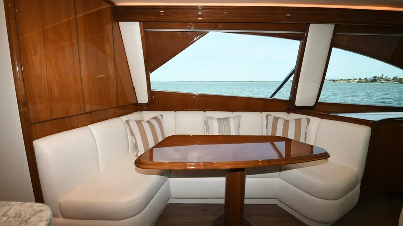 Slide: The Image of Salon Dinette with Ocean View The salon dinette of the 2020 Viking 58 Convertible features elegant wood finishes and plush, white upholstered seating. The large windows provide expansive ocean views, creating a serene dining experience. The table is elegantly crafted, offering both st - 6388300