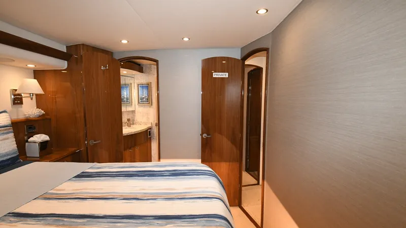 Slide: The Image of Master Stateroom with Ensuite Bath This elegant master stateroom in the 2020 Viking 58 Convertible features a plush, striped bedding ensemble that complements the warm wood finishes. The room is well-lit with recessed lighting, enhancing the spacious feel of the area. An ensuite bathroom i - 6388303