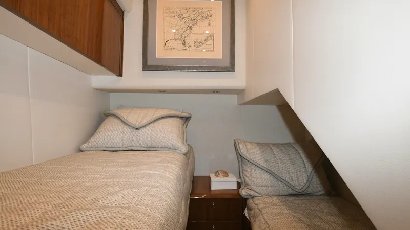 Slide: The Image of Twin Guest Stateroom with Artwork This cozy twin guest stateroom offers comfortable sleeping arrangements with two single beds, perfect for accommodating guests. The warm wood cabinetry and neutral-toned bedding create an inviting atmosphere, complemented by a nautical-themed artwork abov - 6388308