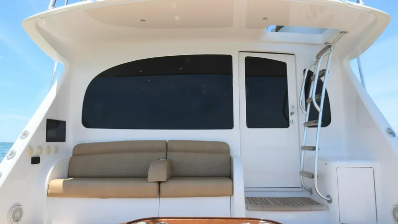 Slide: The Image of Cockpit Seating Area with Ladder Access The cockpit of the 2020 Viking 58 Convertible features a comfortable seating area with plush cushions, perfect for relaxation and socializing. The sleek design includes a polished wood table with integrated cup holders, providing both functionality and el - 6388314
