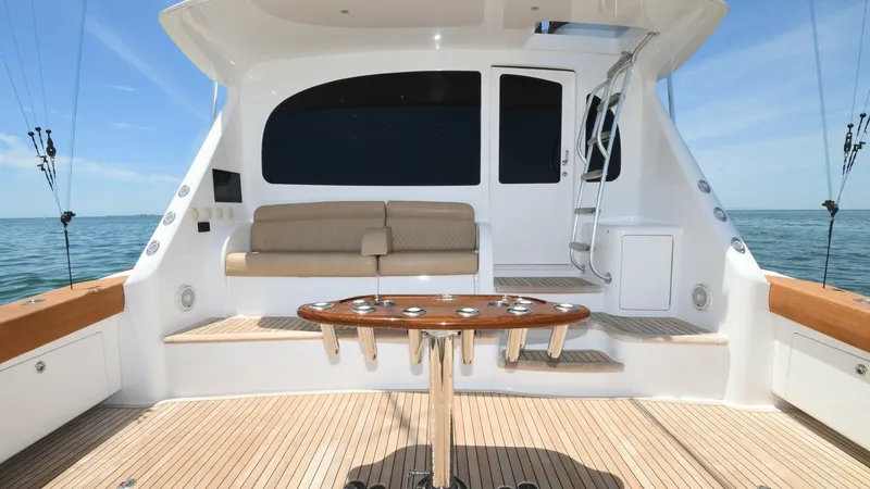Slide: The Image of Spacious Aft Deck with Seating Area The aft deck of the 2020 Viking 58 Convertible features a spacious layout with teak flooring, offering durability and elegance. A comfortable built-in bench provides seating for guests, while the well-placed table is ideal for socializing or fishing activ - 6388288