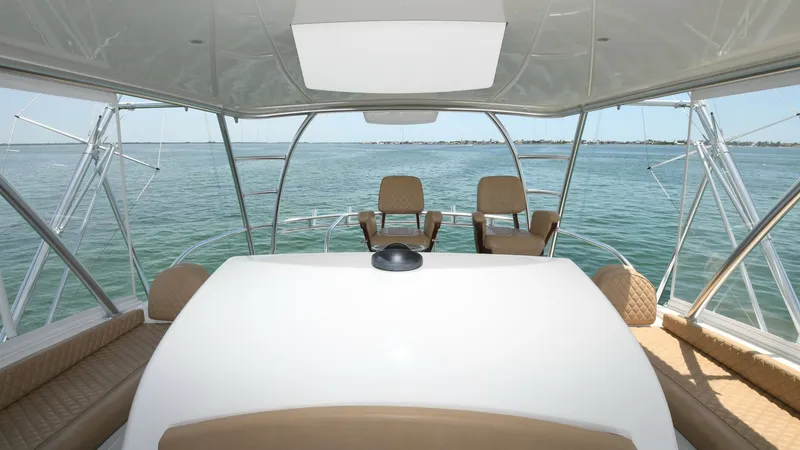 Slide: The Image of Flybridge Helm Area with Seating This image showcases the flybridge helm area of the Viking 58 Convertible, offering commanding views of the open sea. The helm features a sleek, modern console with state-of-the-art navigation equipment, complemented by comfortable, stylish captain and co - 6388318