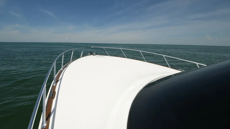 Slide: The Image of Bow View Underway on Open Sea The expansive bow of the 2020 Viking 58 Convertible is showcased, advancing gracefully over open waters. The sleek, white surface is complemented by polished stainless steel railings, providing safety and elegance. This view highlights the yacht's robust - 6388323