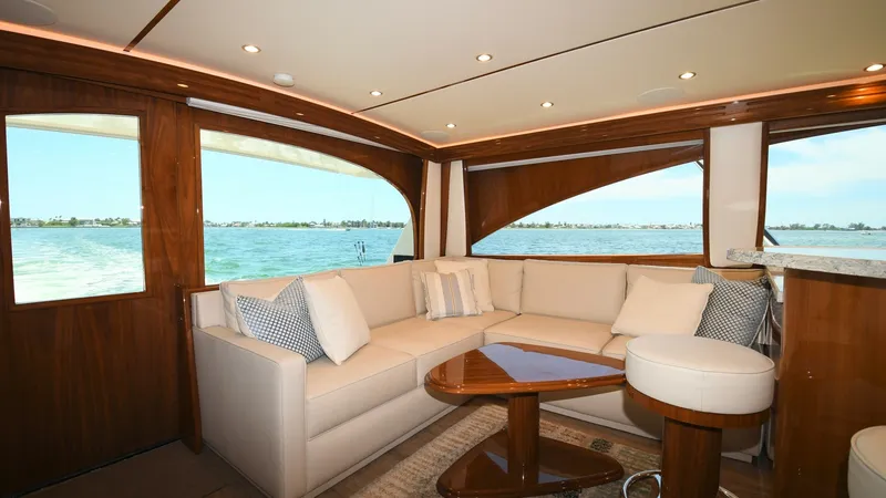 Slide: The Image of Salon with Panoramic Views The salon of the 2020 Viking 58 Convertible boasts an inviting and elegant space with expansive windows that offer breathtaking panoramic views. The plush L-shaped sofa, complemented by a sleek wooden coffee table, provides a perfect setting for relaxatio - 6388291