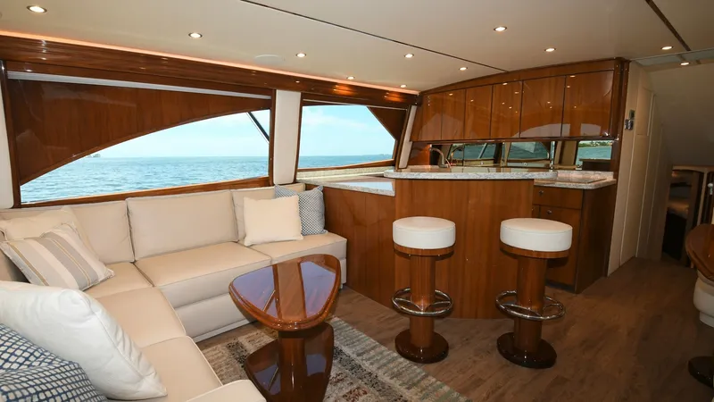 Slide: The Image of Salon and Galley with Ocean View The salon of the 2020 Viking 58 Convertible offers a luxurious and inviting space with plush, cream-colored seating and rich wood finishes. Large windows provide stunning ocean views, enhancing the open and airy feel. The adjacent galley features elegant - 6388293