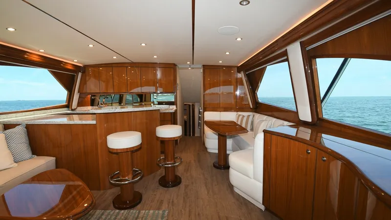 Slide: The Image of Spacious Salon with Ocean Views The salon of the 2020 Viking 58 Convertible offers an inviting space with panoramic ocean views, highlighted by large windows. Rich wood finishes and elegant cabinetry complement the plush seating and bar stools, creating a luxurious and comfortable envir - 6388294