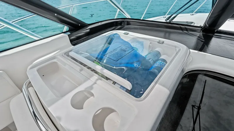 Slide: The Image of Cockpit Refreshment Station This image showcases the cockpit refreshment station on the 2007 Tiara Yachts 32 Open. Featuring a built-in cooler with a clear lid, it offers convenient access to beverages while enjoying the open water. The surrounding cup holders and sleek white finish - 6394592