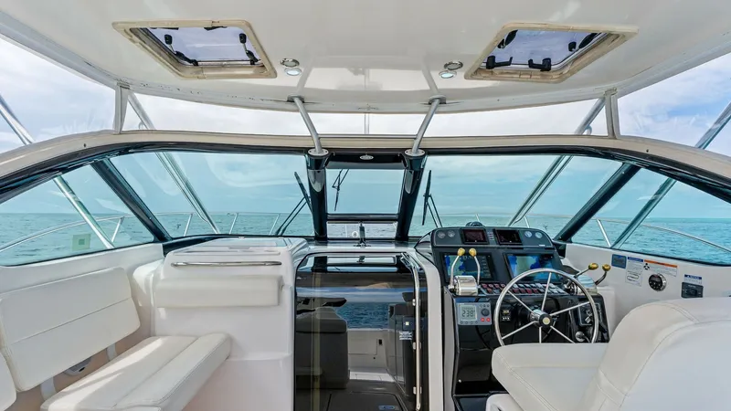 Slide: The Image of Spacious Helm with Seating Area The helm of the Tiara Yachts 32 Open features a sleek, modern dashboard equipped with advanced navigation systems and controls. Comfortable white leather seating surrounds the helm, offering ample space for relaxation and socializing. Large windows provid - 6394596