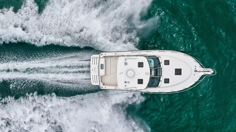 Slide: The Image of Aerial View of Tiara 32 Open This stunning aerial shot captures the Tiara 32 Open cutting through vibrant blue waters with grace and power. The spacious aft deck is clearly visible, showcasing ample space for leisure or fishing activities. The vessel's sleek design is complemented by - 6394614