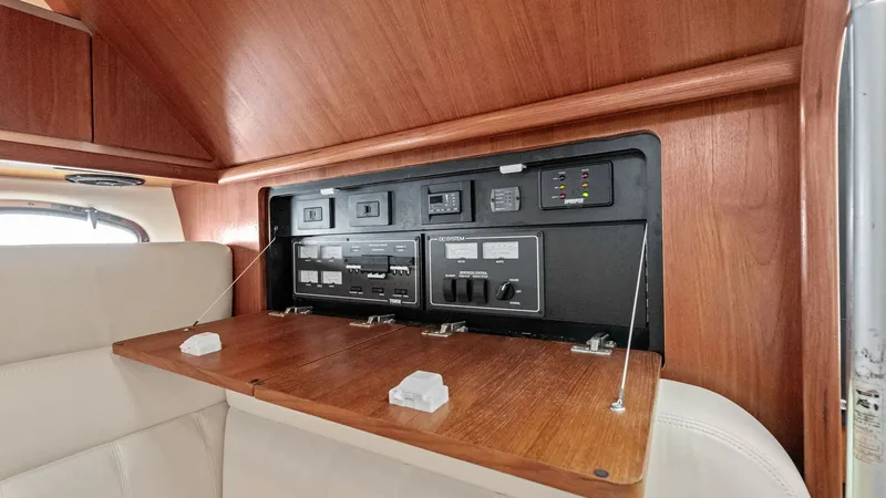 Slide: The Image of Electrical Control Panel Cabinet This image showcases the sleek and organized electrical control panel of the Tiara Yachts 32 Open. The panel is neatly integrated within a wooden cabinet, featuring a fold-down door for easy access. The surrounding wood finish adds a touch of elegance and - 6394575
