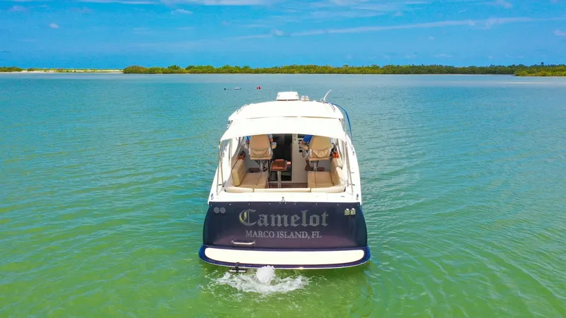 Slide: The Image of Aft View of Camelot on Water The MJM Yachts 29z Camelot is showcased cruising serenely in open waters, highlighting its elegant aft design. The spacious cockpit area offers ample seating, perfect for enjoying panoramic views of the surrounding seascape. The vessel's sleek lines and q - 6479376