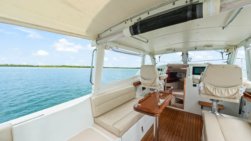 Slide: The Image of Cockpit with Helm Seating and Table This inviting cockpit features elegant teak flooring and a versatile seating layout for comfort and style. The helm station is equipped with plush, adjustable captain's chairs and modern navigation equipment, providing an ideal command center. A polished - 6479396