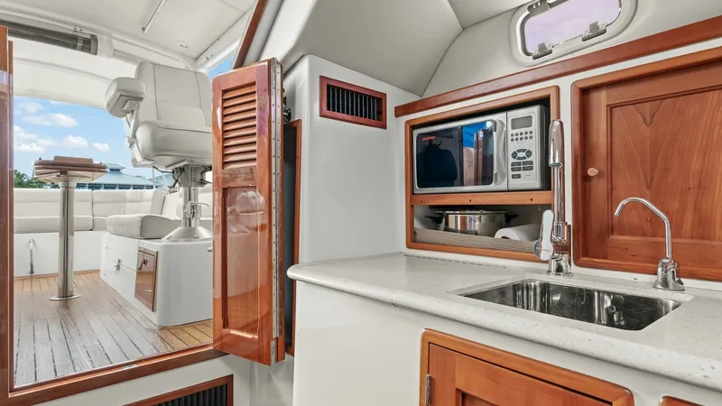 Slide: The Image of Galley with Helm and Seating View This image showcases the well-equipped galley of the 2008 MJM Yachts 29z, featuring a sleek countertop with an integrated sink and rich wooden cabinetry. The adjacent helm area is visible, highlighting a comfortable captain's chair and a spacious seating - 6479412